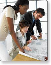Three people looking over a facility blueprint