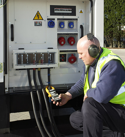 worker checking cables on a generator