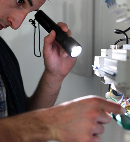 man with flashlight looking at wiring
