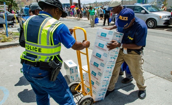 Police officers help distribute water to survivors in the aftermath of a disaster.