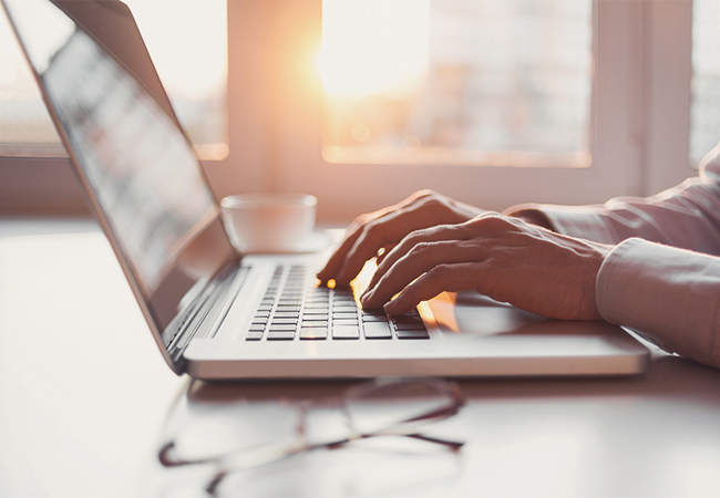 A man's hands typing on a laptop computer.