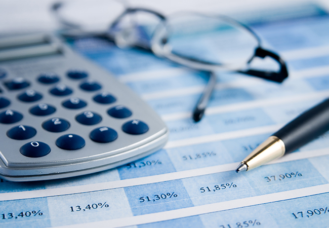 Financial documents with a calculator, pen, and reading glasses.