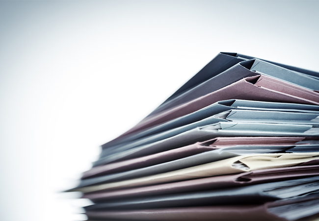 A stack of file folders filled with documents.