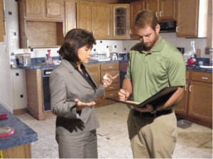 Photograph of adjuster speaking with policyholder in a kitchen.