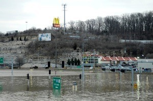 Photograph of flood waters. Buildings in the background along with a McDonalds restaurant sign.