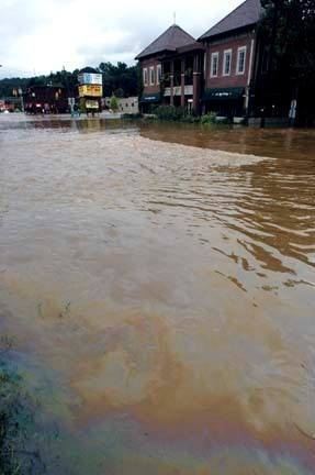 Photograph of polluted flood water flowing down a street.