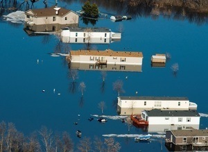Photograph of flooded house and manufactured homes.