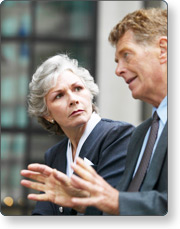 A man in a suit talks while a woman watches him