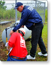 2 FEMA employees looking at a propane tank