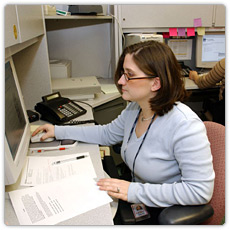 FEMA worker sitting at computer with paperwork in front of her