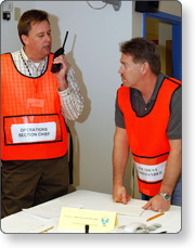 Men in orange vests using a handheld radio.