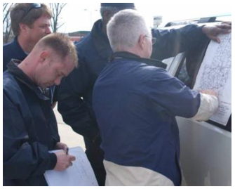 Responders viewing map held up on the side window of a truck.