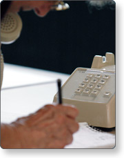 A person writes down information while on the phone