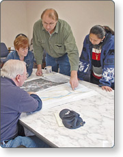 A group of people at a table looking at maps
