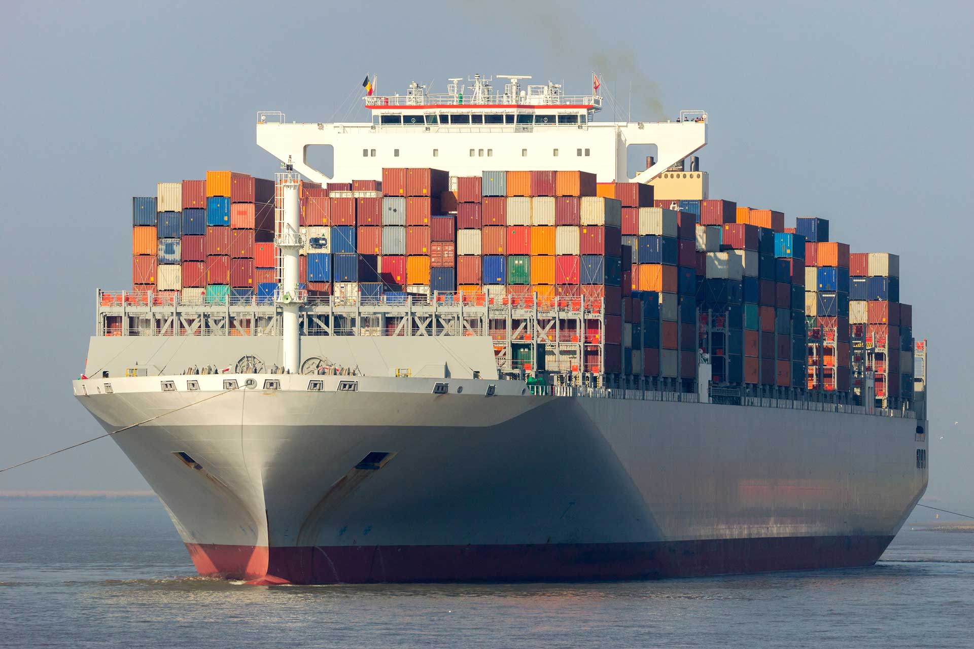 A container ship with hundreds of shipping containers stacked on its top deck.