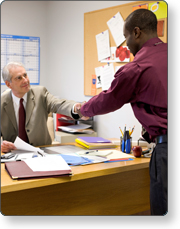 A man sitting at his desk shaking hands with another man