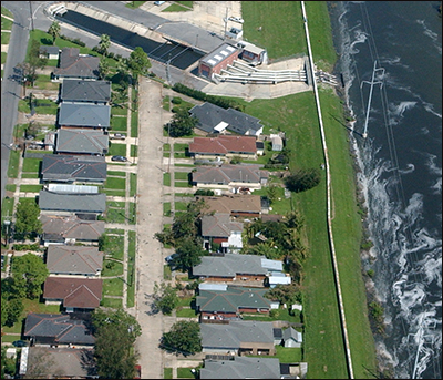 Aerial view of levee. Neighborhoods on one side of the levee are flooded as one side remains dry.