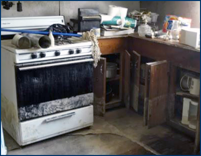 Photo of a kitchen with visible extensive flooding damage, specifically to a large oven, countertops, and cabinets