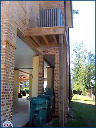 Photo of a portion of a structure exterior showing a condenser unit on a second floor-level platform