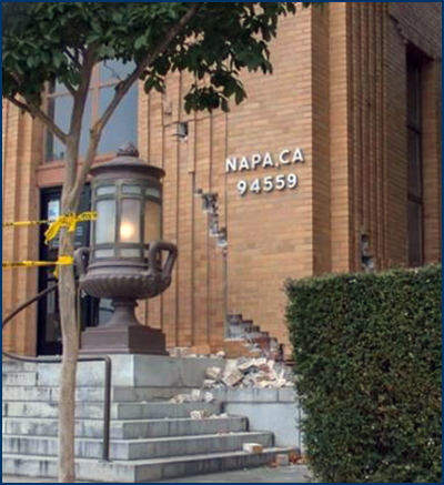 Photo of a brick building showing damage to the lower section of an exterior wall