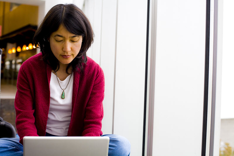 Image shows a woman working on a laptop