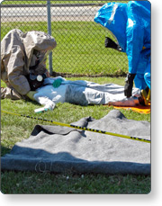two men in protective suits attending to mock victim on the ground