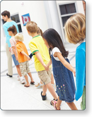 Children in single file line with teacher in front