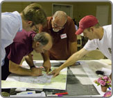 Image of people reading and pointing at plans on a table