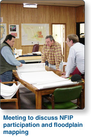 Three Men Discussing Floodplain Mapping, text reads: Meeting to discuss NFIP participatin and floodpain mapping