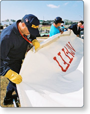 Members of a task force pack up a tent in preparation for demobilization