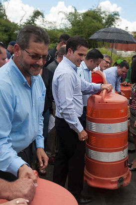Three men in dress shirts are placing orange and white barrels on a road.