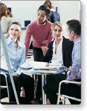 a group of individuals sitting around a table looking at a white board