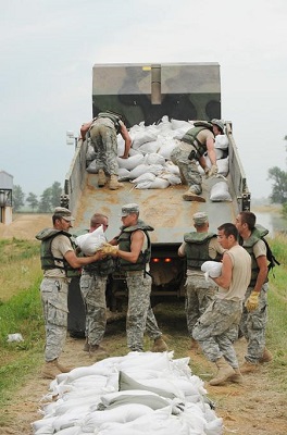 Members of the Missouri National Guard, Army and Air Force National Guard unloading sandbags from a dump truck.