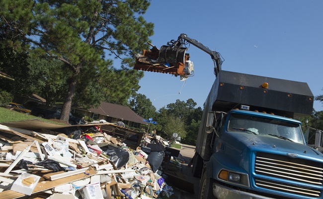 A disposal truck lifts debris.