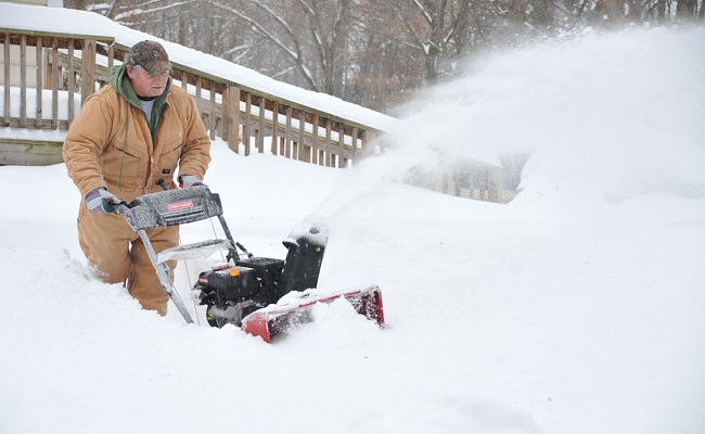 Resident uses a snowblower to dig out after a winter storm