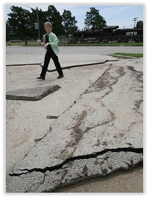 FEMA official looks at asphalt paving that has been moved by the pressure of strong flood waters.