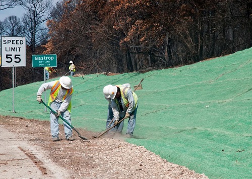 Workers attaching strips of grass onto highway shoulders.