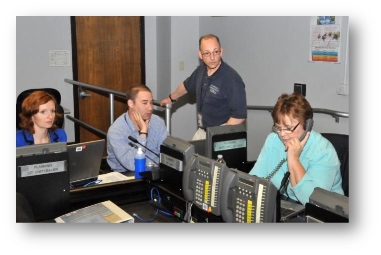 A woman answering a phonecall and other staff working on laptops