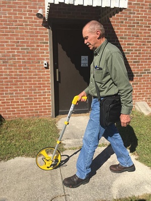 Site Inspector walks with carpenter's measuring tape at site inspection.