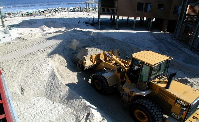 Contracted assistance uses front loaders to remove debris from a beach. By pre-bidding their contracts, Carolina Beach was able to rapidly deploy heavy equipment for debris removal, speeding the recovery process significantly.