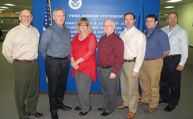 Members of the Region VI Public Assistance Appeal Team posing for a photo in front of the FEMA Mission Statement.