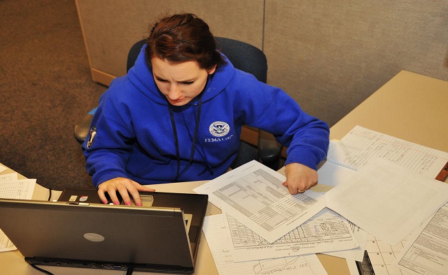 FEMA Corps member works on a project worksheet for the Public Assistance team.