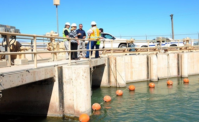 Several men wearing hard hats speaking to one another on a canal.