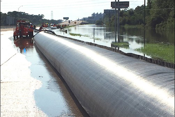 Crews from the Department of Transportation install an aqua dam to prevent flood waters from eroding the highway and allow for motorists to drive safely.