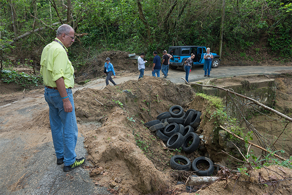 Environmental and historic preservation employees work alongside Public Assistance as they identify an environmental hazard caused by measures taken by the survivors to use tires as landfill for the road that leads to their houses.