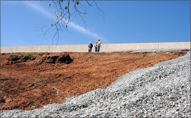 A FEMA Public Assistance Technical Assistance, County Water and Sewer Authority Project Engineer, and FEMA Public Assistance Coordinator are inspecting a breach area of the Dog River Reservoir Dam which failed during severe storms and flooding.