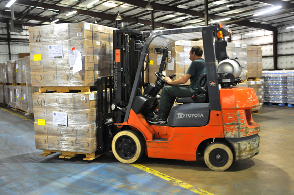 A forklift moves pallets of supplies in a warehouse in Tyler, TX.