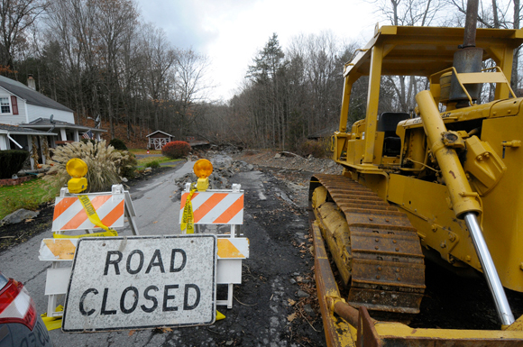 Construction equipment next to a Road Closed sign on a road washed away during Hurricane Irene.