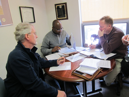 Three people sitting around a table reviewing project information.