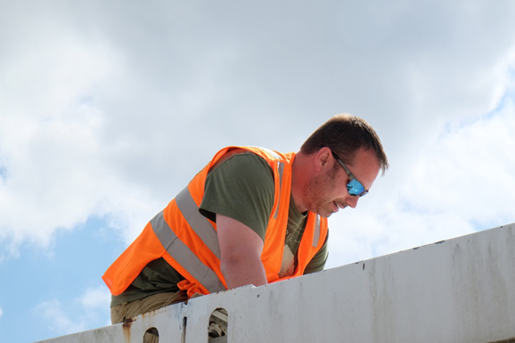 A person in a safety vest working on the roof of a building.